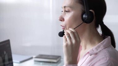 Pembe günlük gömlekli kadın çağrı merkezi operatörü müşterilerine çevrimiçi olarak yardım ediyor. Müşteri desteği sağlıyor ve sorulara cevap veriyor. İş çağrı merkezi.