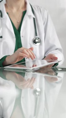 Modern sağlık ortamında dijital tablet kullanan beyaz önlüklü kadın doktor, hasta verileriyle etkileşime geçiyor..