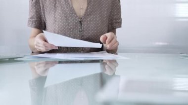 İş kadını ya da kaslı, noktalı bluzlu muhasebeci iyi aydınlatılmış, çağdaş bir ofis ortamında cam bir masada belgeleri tutarken evrak işleriyle uğraşıyor. İş adamları konsepti
