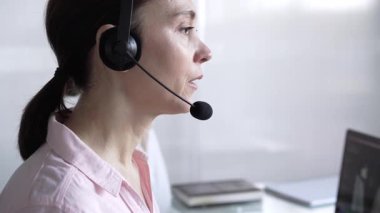 Pembe günlük gömlekli kadın çağrı merkezi operatörü müşterilerine çevrimiçi olarak yardım ediyor. Müşteri desteği sağlıyor ve sorulara cevap veriyor. İş çağrı merkezi.