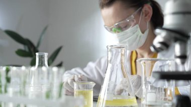 Koruyucu ekipman giyen kadın bilim adamı laboratuvar setinde çalışırken dijital tablet kullanıyor. Görüntüyü kapat. Bilim ve tıp kavramları.