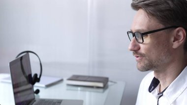 İş adamı ofis çalışanı çevrimiçi toplantıya laptop ve mikrofonla katılıyor, uzaktan evden veya ofisten çalışıyor. İş insanları kavramı.