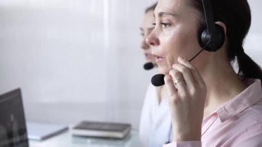 Pembe günlük gömlekli kadın çağrı merkezi operatörü müşterilerine çevrimiçi olarak yardım ediyor. Müşteri desteği sağlıyor ve sorulara cevap veriyor. İş çağrı merkezi.