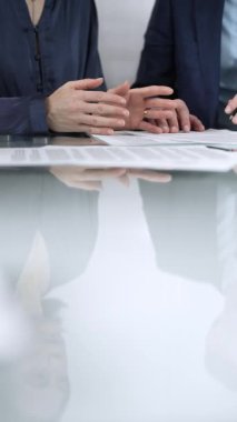 İş adamları bir toplantı sırasında sözleşme şartlarını gözden geçiriyorlar, müzakere ediyorlar ve birlikte kararlar veriyorlar, dikey yakın görüş. Boşluğu kopyala.
