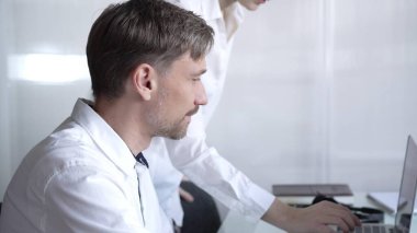 İş arkadaşları bir proje üzerinde işbirliği yapıyor, laptoptaki verileri gözden geçiriyor ve modern bir ofiste üretken bir tartışmaya giriyorlar. İş adamları konsepti.