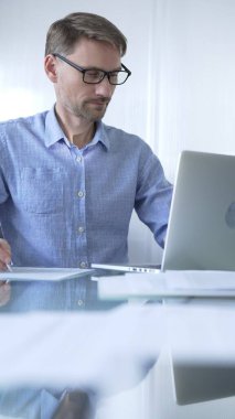 Sıradan giyimli iş adamı, modern bir ofiste verimliliği artıran temiz ve parlak bir çevreye sahip bir dizüstü bilgisayar kullanıyor. İş adamları konsepti.