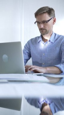 Sıradan giyimli iş adamı, modern bir ofiste verimliliği artıran temiz ve parlak bir çevreye sahip bir dizüstü bilgisayar kullanıyor. İş adamları konsepti.