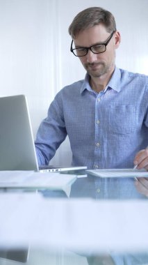 Sıradan giyimli iş adamı, modern bir ofiste verimliliği artıran temiz ve parlak bir çevreye sahip bir dizüstü bilgisayar kullanıyor. İş adamları konsepti.