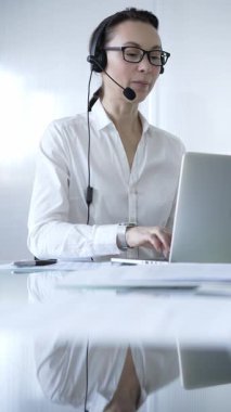 Kulaklık takan ve dizüstü bilgisayarda çalışan kadın sekreter, müşteri desteği ya da çevrimiçi hizmet sağlıyor. İş adamları konsepti.