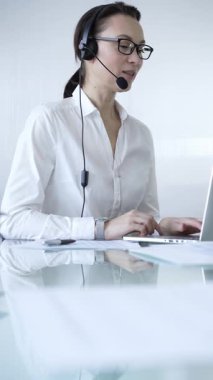 Kulaklık takan ve dizüstü bilgisayarda çalışan kadın sekreter, müşteri desteği ya da çevrimiçi hizmet sağlıyor. İş adamları konsepti.