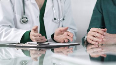 Tıbbi konsültasyon sırasında hastaya teşhis koyarken el kol hareketi yapan doktor, sağlık kararlarına destek ve rehberlik sunuyor..