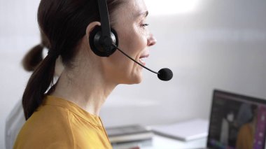 Mavi günlük bluzlu odaklı kadın çağrı merkezi operatörü müşterilerine çevrimiçi olarak yardım ediyor, müşteri desteği sağlıyor ve sorulara cevap veriyor. Çağrı merkezi kavramı.