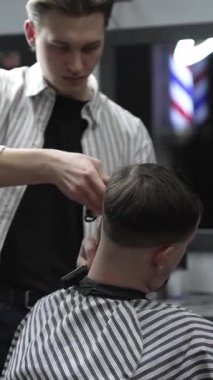 Profesyonel berber müşterilerin saçlarını elektrikli makasla dikkatlice buduyor, modern bir berber dükkanında şık ve kusursuz bir saç kesimi sağlıyor.