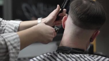 Profesyonel berber, erkek müşterinin boynundaki kılları elektrikli makasla dikkatlice buduyor ve modern berber dükkanında titiz bir bakım hizmeti sunuyor.