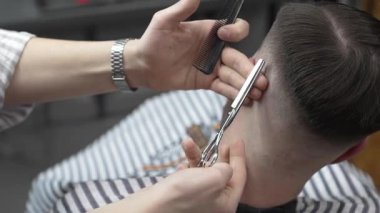 Profesyonel berber, müşterilerin saçlarını buduyor, makas ve tarakla kusursuz bir solukluk çiziyor, çağdaş berber dükkânı düzenliyor, uzman tımar ediyor.