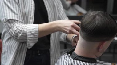 Profesyonel berber müşterilerin saçlarını elektrikli makasla dikkatlice buduyor, modern bir berber dükkanında şık ve kusursuz bir saç kesimi sağlıyor.