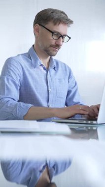 Sıradan giyimli iş adamı, modern bir ofiste verimliliği artıran temiz ve parlak bir çevreye sahip bir dizüstü bilgisayar kullanıyor. İş adamları konsepti.