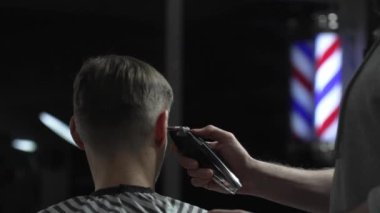 Modern bir berber dükkanında erkek müşterinin saçını ustalıkla kesen profesyonel berber stili ve çağdaş bir saç kesimi kişisel tarzını geliştirir.