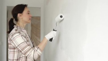 Profesyonel bir ressam koruyucu eldivenler giyerek duvarda pürüzsüz bir şekilde beyaz boya sürüyor, evin içini kusursuz bir fırça ve titiz bir boya tekniğiyle yeniliyor.
