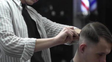 Profesyonel berber saç kesiminden önce müşteri saçını tarıyor, berber dükkanında stil yapmaya hazırlanıyor, erkekler için modern saç stili yaratıyor, güzellik salonu hizmeti veriyor.