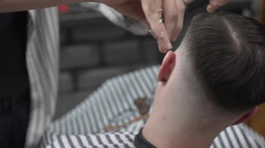 Profesyonel berber, müşterilerin saçlarını buduyor, makas ve tarakla kusursuz bir solukluk çiziyor, çağdaş berber dükkânı düzenliyor, uzman tımar ediyor.