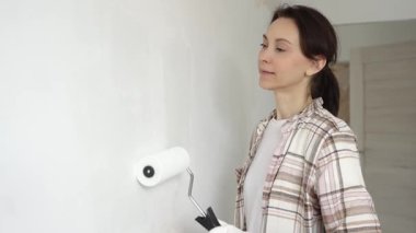 Profesyonel bir ressam koruyucu eldivenler giyerek duvarda pürüzsüz bir şekilde beyaz boya sürüyor, evin içini kusursuz bir fırça ve titiz bir boya tekniğiyle yeniliyor.