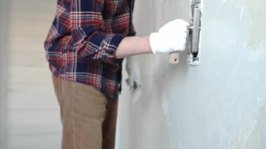 Eldiven takan ve işe odaklanan kimliği belirsiz erkek inşaat işçisi, sürmekte olan bir ev yenileme projesi sırasında duvara ustalıkla alçı yapıştırmak, yüzeyi düzleştirmek ve kapamak için mala kullanıyor.