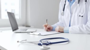 Mavi steteskopun yakın çekimi klinikteki panoda bayan doktor profesyonel yazısının yanında duruyor. Tıp ve sağlık hizmetleri kavramı.