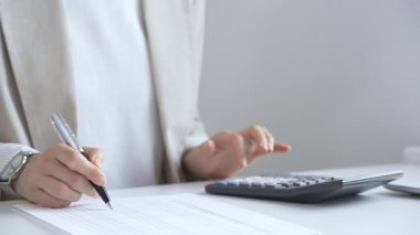 Yıllık vergisini hesaplayan profesyonel muhasebeci, mali belgeleri gözden geçiren, iş yerindeki bütçe detaylarını hesap makinesi ve evrak işleriyle takip eden. Ticarette denetim ve vergiler