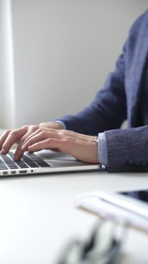 Profesyonel iş adamı dizüstü bilgisayar klavyesinde daktilo kullanıyor, çağdaş çalışma alanında özel dikim takım elbise ve kol saati giyerken dikkatle çalışıyor. İş adamları konsepti