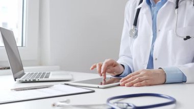 Laboratuvar önlüğü ve steteskop giyen kadın doktor, modern sağlık teknolojisini sergilemek için bilgisayarlı tablet kullanıyor. Tıp konsepti.