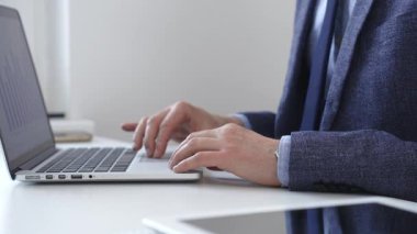 Profesyonel iş adamı dizüstü bilgisayar klavyesinde daktilo kullanıyor, çağdaş çalışma alanında özel dikim takım elbise ve kol saati giyerken dikkatle çalışıyor. İş adamları konsepti