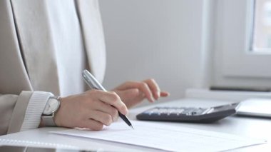 Yıllık vergisini hesaplayan profesyonel muhasebeci, mali belgeleri gözden geçiren, iş yerindeki bütçe detaylarını hesap makinesi ve evrak işleriyle takip eden. Ticarette denetim ve vergiler