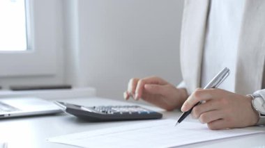 Yıllık vergisini hesaplayan profesyonel muhasebeci, mali belgeleri gözden geçiren, iş yerindeki bütçe detaylarını hesap makinesi ve evrak işleriyle takip eden. Ticarette denetim ve vergiler