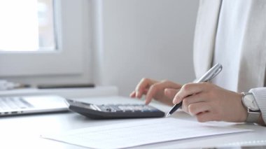 Yıllık vergisini hesaplayan profesyonel muhasebeci, mali belgeleri gözden geçiren, iş yerindeki bütçe detaylarını hesap makinesi ve evrak işleriyle takip eden. Ticarette denetim ve vergiler