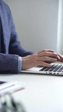 Profesyonel iş adamı dizüstü bilgisayar klavyesinde daktilo kullanıyor, çağdaş çalışma alanında özel dikim takım elbise ve kol saati giyerken dikkatle çalışıyor. İş adamları konsepti