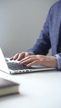 Profesyonel iş adamı dizüstü bilgisayar klavyesinde daktilo kullanıyor, çağdaş çalışma alanında özel dikim takım elbise ve kol saati giyerken dikkatle çalışıyor. İş adamları konsepti