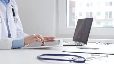 Laboratuvar önlüğü ve steteskop giyen kadın doktor, modern sağlık teknolojisini sergilemek için bilgisayarlı tablet kullanıyor. Tıp konsepti.