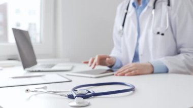 Laboratuvar önlüğü ve steteskop giyen kadın doktor, modern sağlık teknolojisini sergilemek için bilgisayarlı tablet kullanıyor. Tıp konsepti.