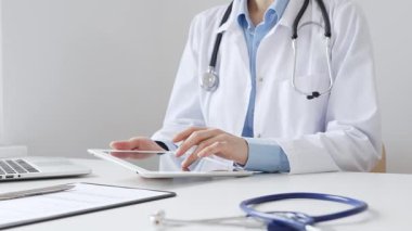 Laboratuvar önlüğü ve steteskop giyen kadın doktor, modern sağlık teknolojisini sergilemek için bilgisayarlı tablet kullanıyor. Tıp konsepti.