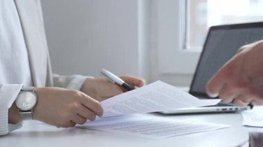 Saat takan iş kadını, ofis masasında bir kontrat imzalıyor. Yanında dizüstü bilgisayar ve diğer belgeler var. Bu da verimli bir iş günü olduğunu gösteriyor. İş adamları konsepti