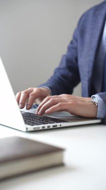 Profesyonel iş adamı dizüstü bilgisayar klavyesinde daktilo kullanıyor, çağdaş çalışma alanında özel dikim takım elbise ve kol saati giyerken dikkatle çalışıyor. İş adamları konsepti