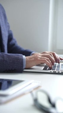 Profesyonel iş adamı dizüstü bilgisayar klavyesinde daktilo kullanıyor, çağdaş çalışma alanında özel dikim takım elbise ve kol saati giyerken dikkatle çalışıyor. İş adamları konsepti