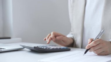 Yıllık vergisini hesaplayan profesyonel muhasebeci, mali belgeleri gözden geçiren, iş yerindeki bütçe detaylarını hesap makinesi ve evrak işleriyle takip eden. Ticarette denetim ve vergiler