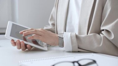 İş kadını kol saati takıyor. Ofis masasında not defteri ve gözlüklü dijital tablet kullanıyor. İnternette geziniyor veya internette çalışıyor. İş adamları konsepti