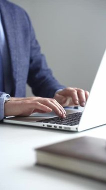 Profesyonel iş adamı dizüstü bilgisayar klavyesinde daktilo kullanıyor, çağdaş çalışma alanında özel dikim takım elbise ve kol saati giyerken dikkatle çalışıyor. İş adamları konsepti