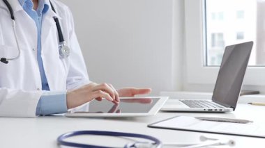Laboratuvar önlüğü ve steteskop giyen kadın doktor, modern sağlık teknolojisini sergilemek için bilgisayarlı tablet kullanıyor. Tıp konsepti.