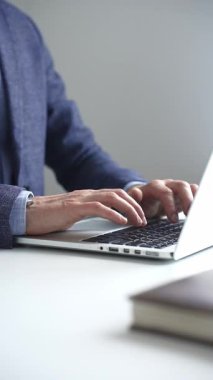 Profesyonel iş adamı dizüstü bilgisayar klavyesinde daktilo kullanıyor, çağdaş çalışma alanında özel dikim takım elbise ve kol saati giyerken dikkatle çalışıyor. İş adamları konsepti