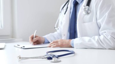 Mavi steteskop, klinikteki panoda doktor adamın profesyonel yazısının yanında duruyor. Tıp ve sağlık hizmetleri kavramı.