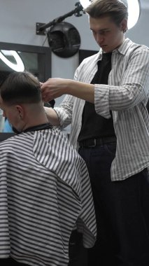 Profesyonel berber müşterilerin saçlarını elektrikli makasla dikkatlice buduyor, modern bir berber dükkanında şık ve kusursuz bir saç kesimi sağlıyor..